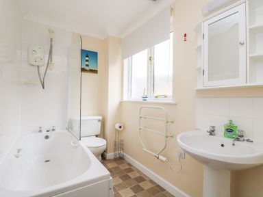 A bathroom with a bathtub shower toilet sink and window at Pugwash Cottage in Falmouth