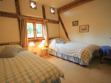 A bedroom with two single beds and table lamps near a window at Whites Farm Barn Ledbury