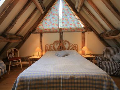 A bedroom with a double bed a chair bedside tables with lamps and a window with floral curtains at Whites Farm Barn Ledbury
