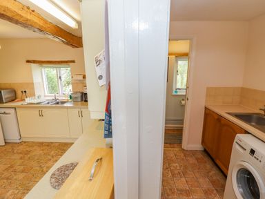 A kitchen with a sink microwave and dishwasher and a utility room with a washing machine and sink at Pheasant Cottage in Minster Lovell