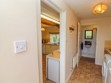 A hallway with tiled floor leading to a kitchen and a small room with a sink at Pheasant Cottage in Minster Lovell