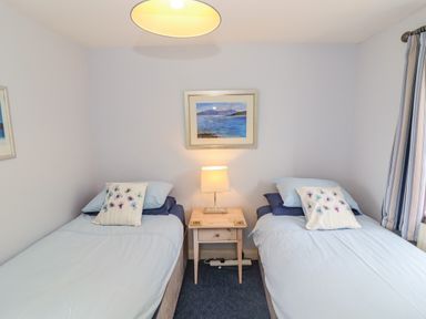 A bedroom with two single beds a wooden nightstand with a lamp and a framed picture on the wall at Pheasant Cottage in Minster Lovell
