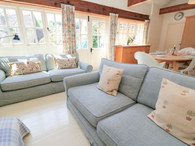 A living room with sofas and a dining area at Upper Mill Barn in Coln St Aldwyns near Bibury