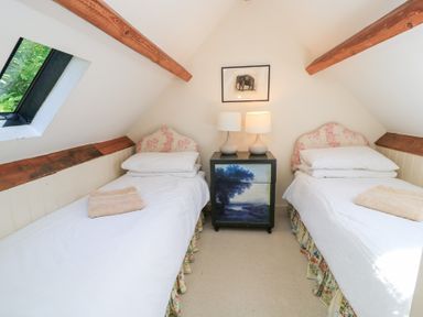 A bedroom with two single beds and a black bedside table at Upper Mill Barn, Coln St Aldwyns, near Bibury
