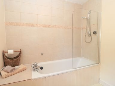 A bathroom with a bathtub and shower at Upper Mill Barn in Coln St Aldwyns, near Bibury