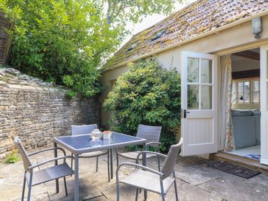 An outdoor area with a table and chairs at Upper Mill Barn, Coln St Aldwyns, near Bibury