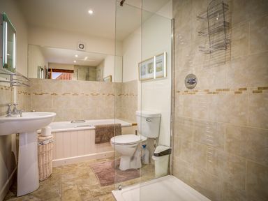 A bathroom with a pedestal sink a bathtub a toilet a glass shower enclosure and a mirror at Top Barn in Chipping Norton