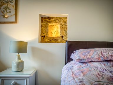 A bedroom with a bedside table lamp and a bed with patterned bedding at Top Barn in Chipping Norton