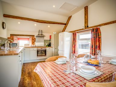 A kitchen with a dining table set with plates glasses and cutlery at Top Barn in Chipping Norton