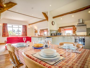 A kitchen and dining area with a table set for four and a red sofa in the background at Top Barn in Chipping Norton