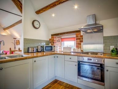 A kitchen with wooden countertops appliances and a clock on the wall at Top Barn in Chipping Norton