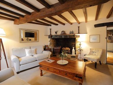 A living room with a stone fireplace a wooden coffee table and sofas at Pike Cottage in Stow-On-The-Wold