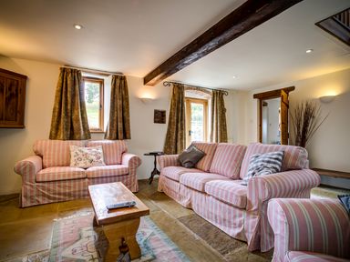 A living room with striped sofas wooden coffee table and patterned curtains at Little Barn in Ascott near Chipping Norton