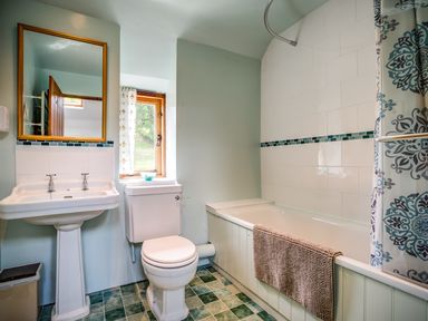 A bathroom with a pedestal sink toilet bathtub with shower curtain and window at Little Barn in Ascott near Chipping Norton