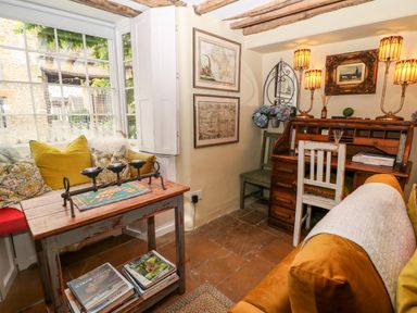 A small room with a wooden desk and chair a seating area with cushions and a window with shutters at Benfield in Stow-on-the-Wold