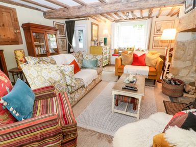 A living room with sofas a coffee table cushions and a wooden cabinet at Benfield in Stow-on-the-Wold