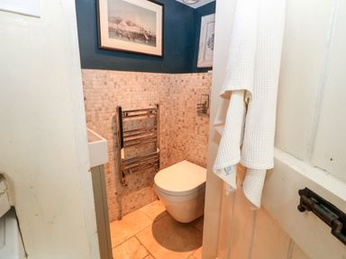 A small bathroom with a wall-mounted toilet stainless steel towel rack and a framed picture on the wall at Benfield in Stow-on-the-Wold
