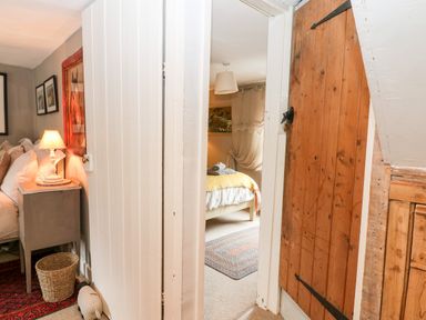 A view through a small hallway showing parts of two bedrooms with wooden doors and bedside tables at Benfield in Stow-on-the-Wold
