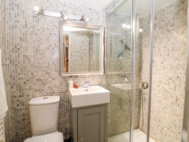 A bathroom with a toilet sink mirror and a glass enclosed shower at Benfield in Stow-on-the-Wold