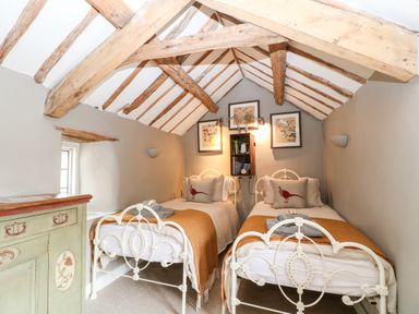 A small bedroom with two single beds featuring white metal frames under a wooden beamed ceiling at Benfield in Stow-on-the-Wold