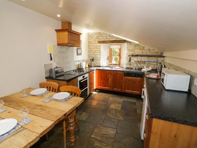 A kitchen with a table and chairs at Robbie's Barn Fulready near Stratford-upon-Avon