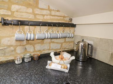 A kitchen with mugs hanging, a kettle, jars, eggs, and a plate of cookies at Robbie's Barn Fulready near Stratford-upon-Avon