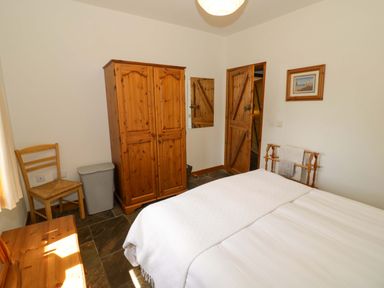 A bedroom with a bed and wardrobe at Robbie's Barn in Fulready near Stratford-upon-Avon