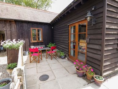 An outdoor patio with a table and chairs at Robbie's Barn in Fulready near Stratford-upon-Avon