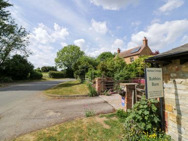 A cottage with a sign in front at Robbie's Barn Fulready near Stratford-upon-Avon