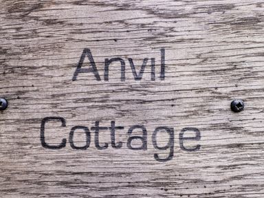 A wooden sign with the text Anvil Cottage