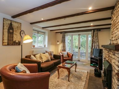 A living room with leather chairs a sofa a wooden coffee table and a stone fireplace at Anvil Cottage in Chipping Norton