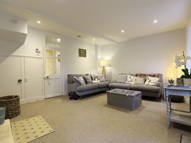 A living room with two grey sofas a wicker chest a floor lamp and a side table with a plant at Hare House in Chipping Norton