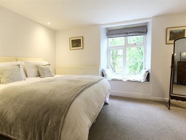 A bedroom with a double bed pillows window seat and mirror at Hare House in Chipping Norton
