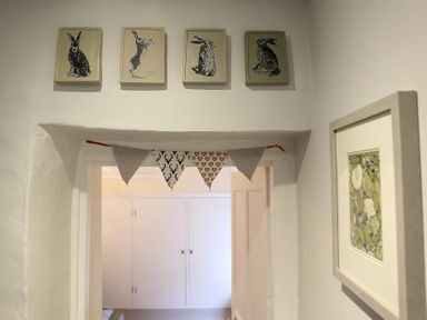 A doorway with four framed rabbit illustrations above and fabric bunting hanging across at Hare House in Chipping Norton