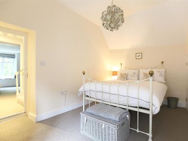 A bedroom with a metal bed frame pillows a lamp and a woven basket at Hare House in Chipping Norton