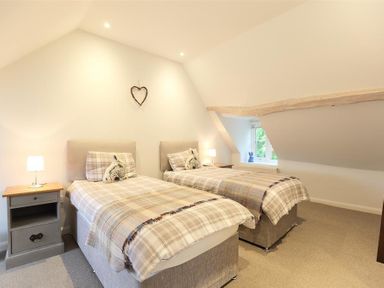 A bedroom with two single beds and nightstands with lamps at Hare House in Chipping Norton