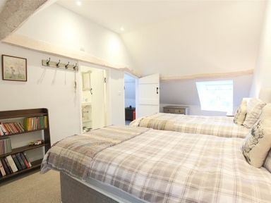 A bedroom with two single beds a bookshelf and a window at Hare House in Chipping Norton