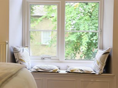A window seat with patterned cushions and pillows in a bedroom at Hare House in Chipping Norton