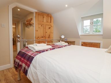 A bedroom with a bed with white bedding and folded towels near a window at The Cottage At Barrow Mead in Bath