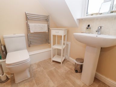 A bathroom with a toilet sink towel rack and small storage unit at The Cottage At Barrow Mead in Bath