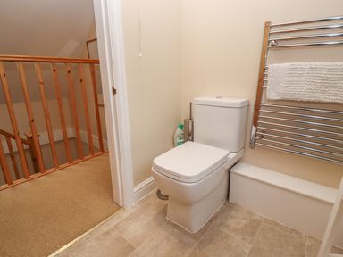 A bathroom with a toilet and a chrome towel rail with a white towel at The Cottage At Barrow Mead in Bath