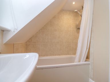 A bathroom with a bathtub shower combination and a sink at The Cottage At Barrow Mead in Bath
