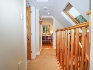 A hallway with carpet floor wooden railing skylight and a bedroom visible at The Cottage At Barrow Mead in Bath
