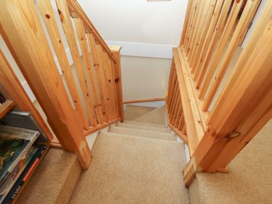 A staircase with wooden railings and carpeted steps next to a bookshelf at The Cottage At Barrow Mead in Bath