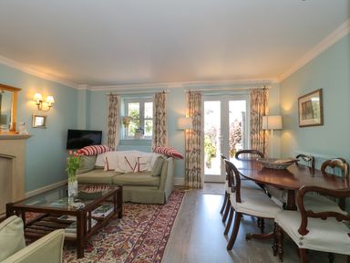 A living room with a sofa dining table and chairs and French doors at Batemans Nailsworth