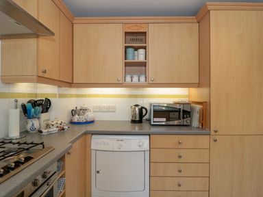 A kitchen with wooden cabinets gray countertops a dishwasher microwave kettle and cooking utensils at Batemans Nailsworth