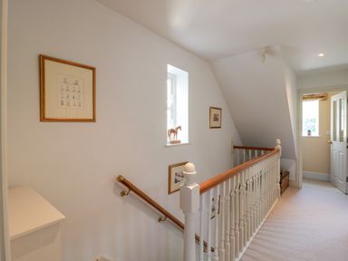 A hallway with a wooden handrail and framed pictures on the walls at Batemans in Nailsworth