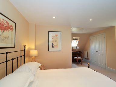A bedroom with a bed a bedside lamp a framed picture a chair and a dressing table at Batemans Nailsworth
