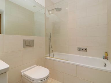 A bathroom with a toilet and a bathtub with shower at Hazel Manor Wing in Painswick