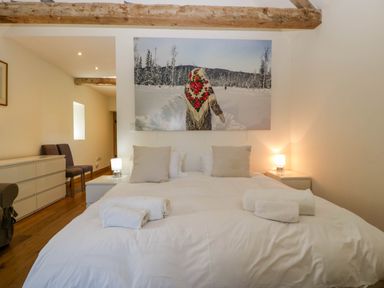A bedroom with a large bed two bedside tables and lamps a dresser and two chairs at Hazel Manor Wing in Painswick
